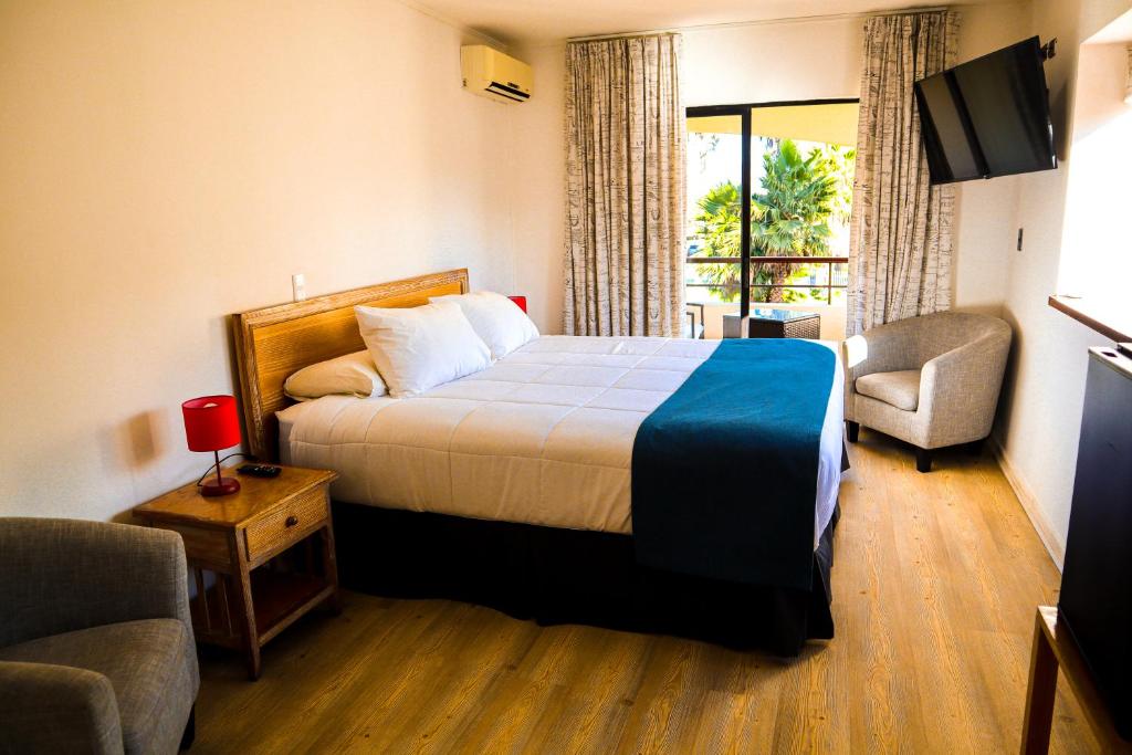a hotel room with a bed and a balcony at Hotel Palmas de La Serena in La Serena