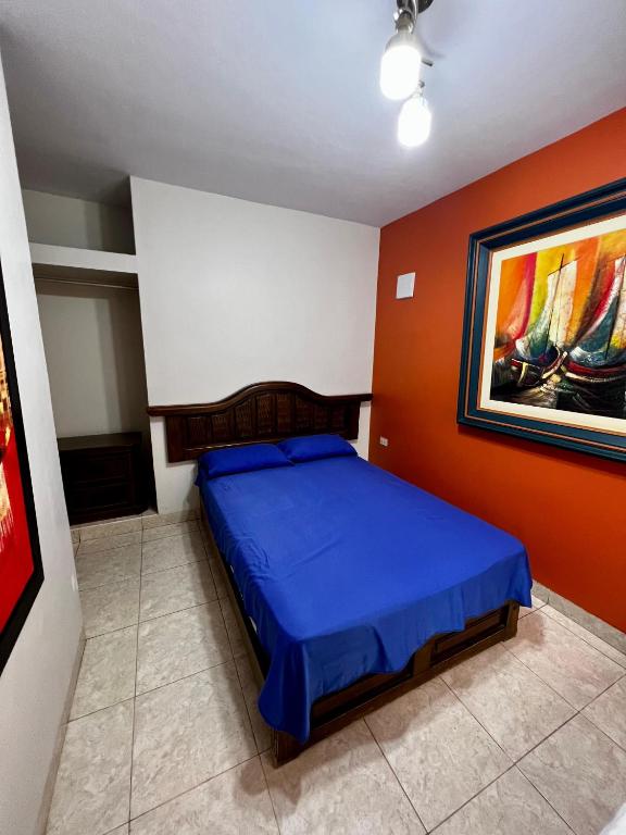 um quarto com uma cama azul e um quadro na parede em Carolina's Hostel em Piura