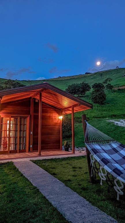 a wooden cabin with a hammock in front of it at Chalé Faisão Recanto Buscapé SFX in São Francisco Xavier