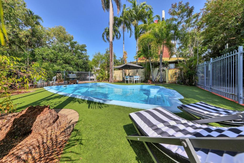 a swimming pool with two lounge chairs and a fence at Paravista Motel in Darwin