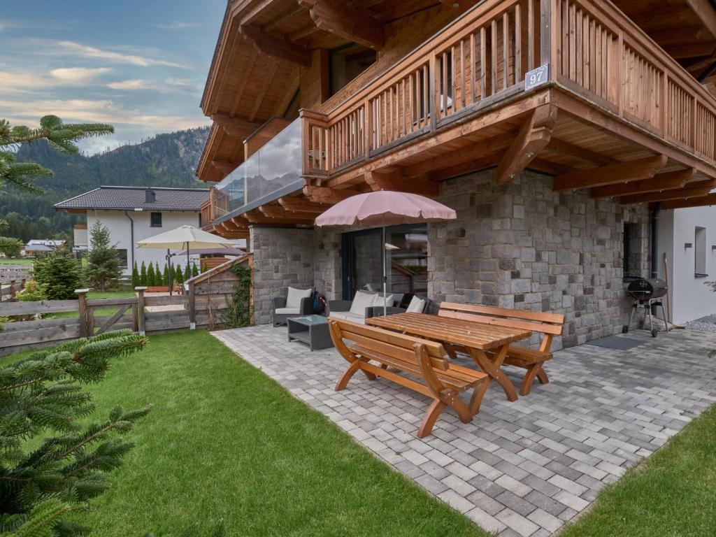 un banco de madera sentado en un patio bajo un balcón en Lodge Elise en Wald im Pinzgau