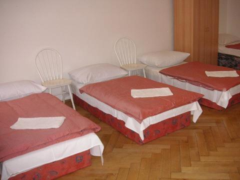 プラハにあるホステル ベルの赤と白のカバーが付いた部屋のベッド3台