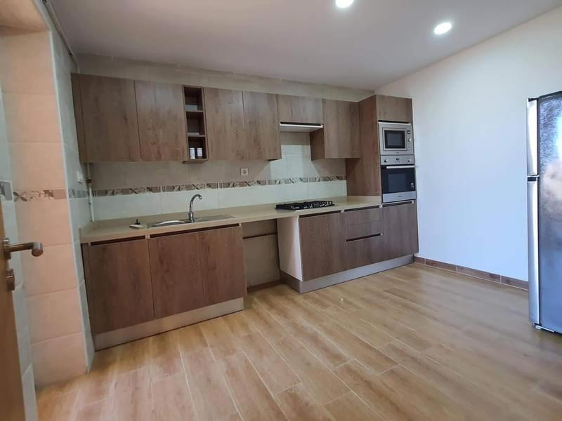 a kitchen with wooden cabinets and a counter top at Très beaux F4 Annaba in Zonka