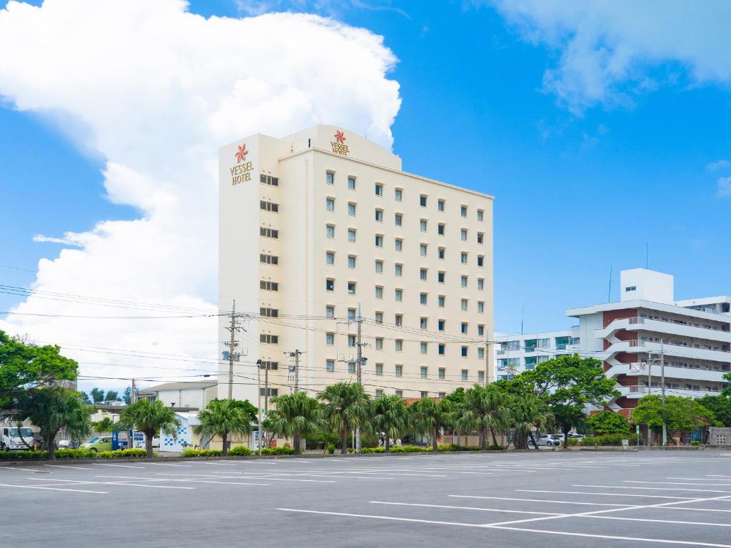 ein großes weißes Gebäude mit einem Parkplatz davor in der Unterkunft Vessel Hotel Ishigakijima in Ishigaki-jima