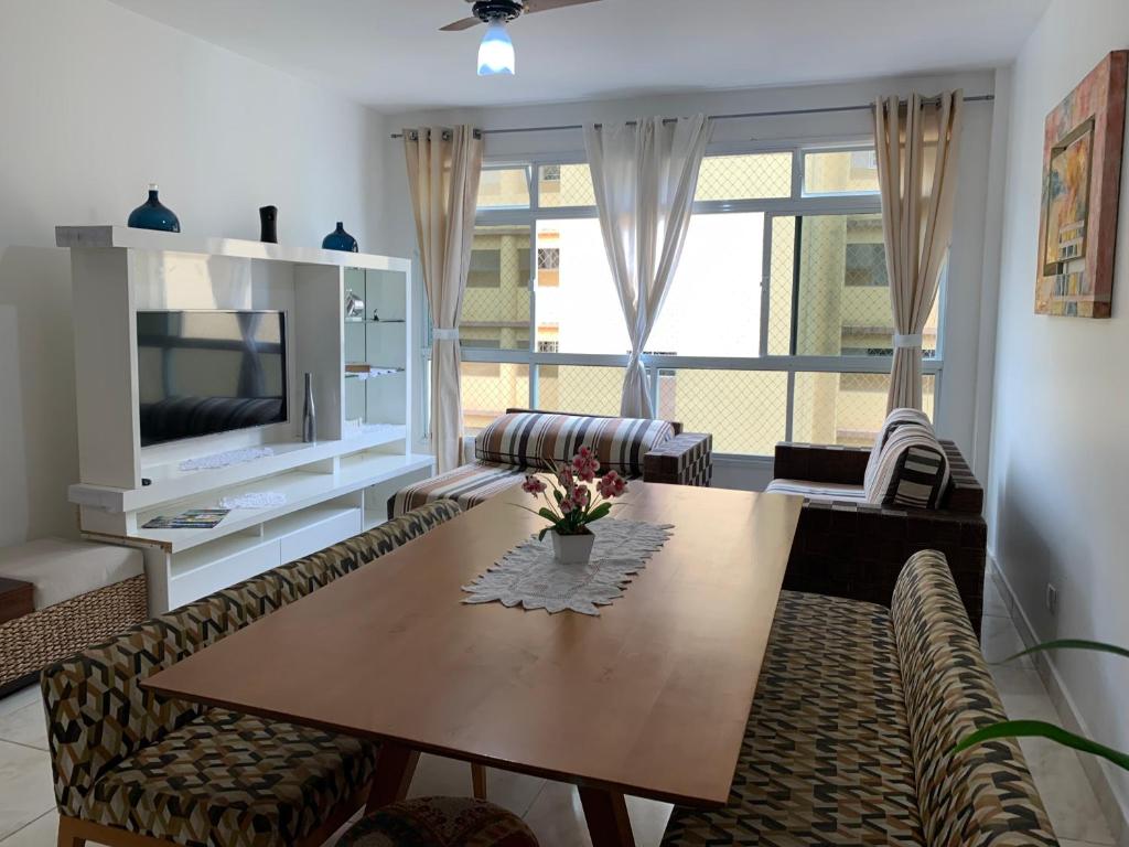 a living room with a table and chairs and a television at Beautiful condo by the shore in Santos