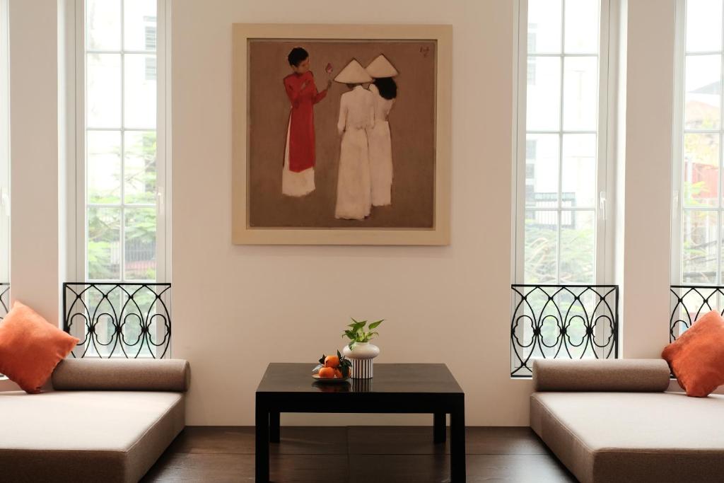 una sala de estar con 2 sofás y una pintura en la pared en Paul Chabot Hotel en Hai Phong