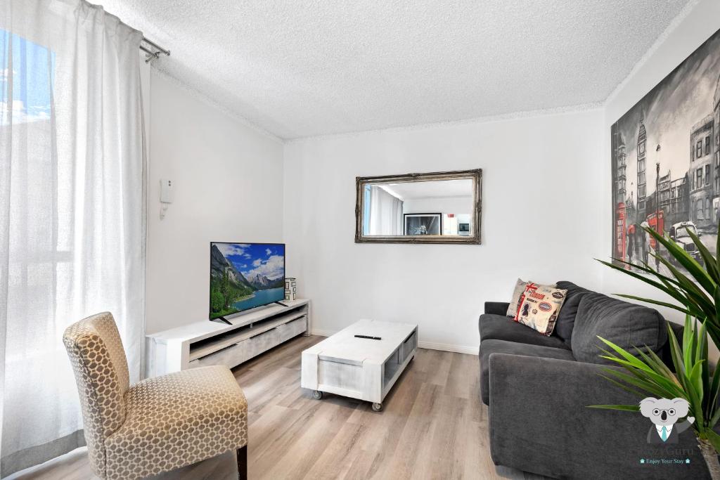 ein Wohnzimmer mit einem Sofa und einem TV in der Unterkunft KozyGuru Redfern Charming 1 Bed Parking NRE012 in Sydney