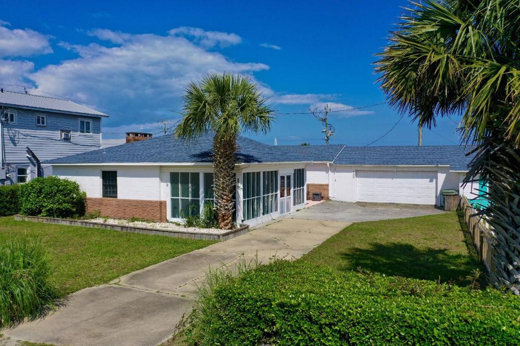 a house with a palm tree in the driveway at Lorraine's Beach Cottage in Kure Beach
