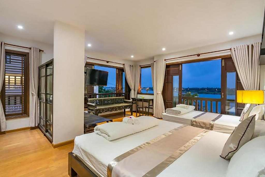 a large bedroom with two beds and a balcony at B'Lan Riverside Villa in Hoi An