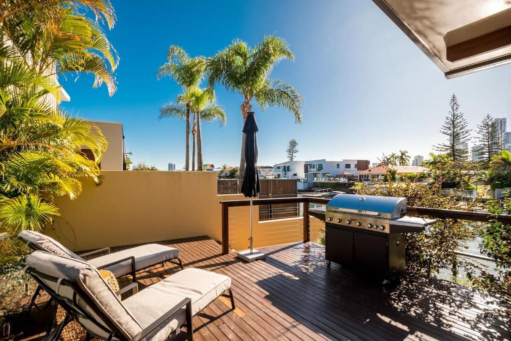 a patio with a grill on a deck with palm trees at Waterfront Retreat with Private Dock-Isle of Capri in Gold Coast