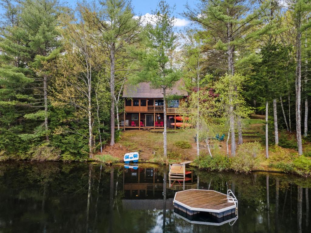 une maison sur un lac avec un bateau dans l'eau dans l'établissement Private Lakefront! - Luxury Log House!, à Sanbornton