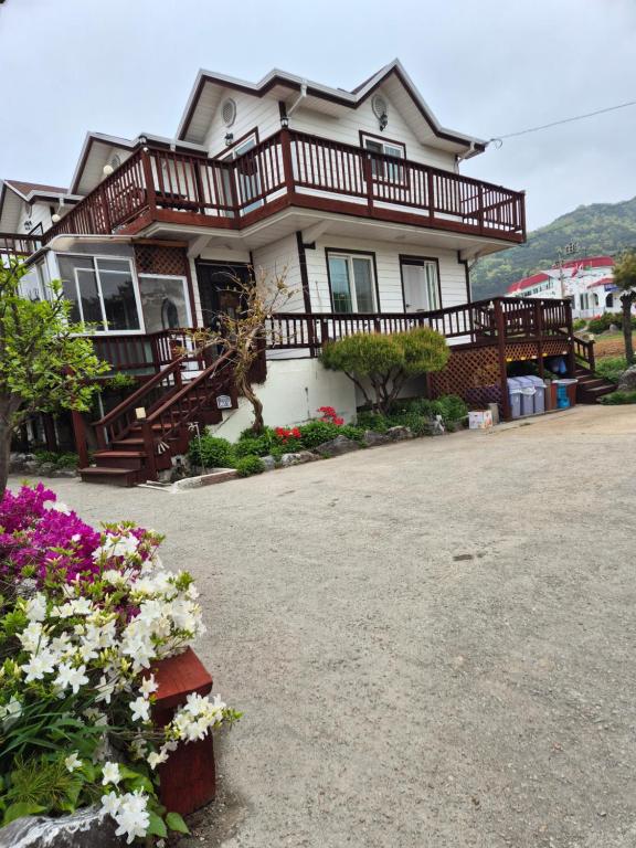 a house with a porch and flowers in front of it at Ganghwa Sweet House Pension in Incheon