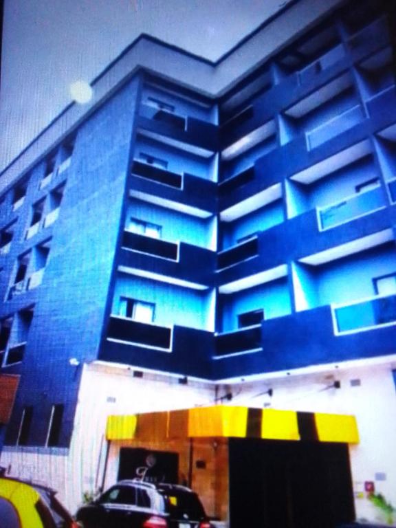 Un bâtiment bleu avec une voiture garée devant. dans l'établissement Villa toscana luxe hotel port Harcourt, à Port Harcourt