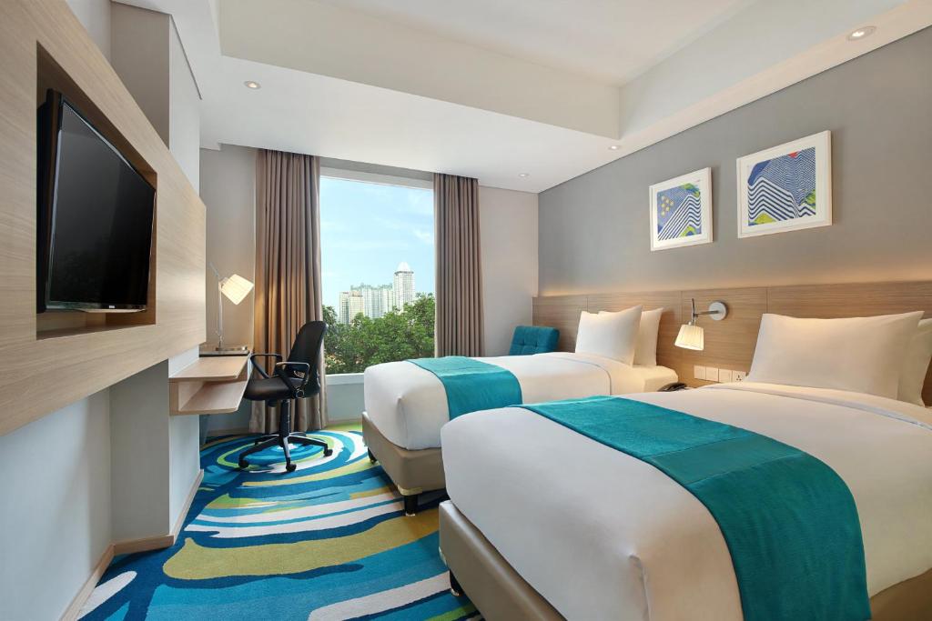 a hotel room with two beds and a flat screen tv at Holiday Inn Express Jakarta Wahid Hasyim, an IHG Hotel in Jakarta