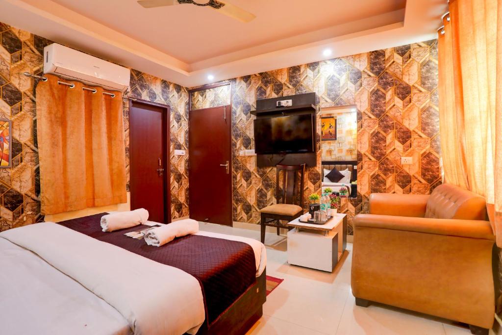 ein Schlafzimmer mit einem Bett, einem TV und einem Sofa in der Unterkunft GRAND HOMESTAY in Neu-Delhi