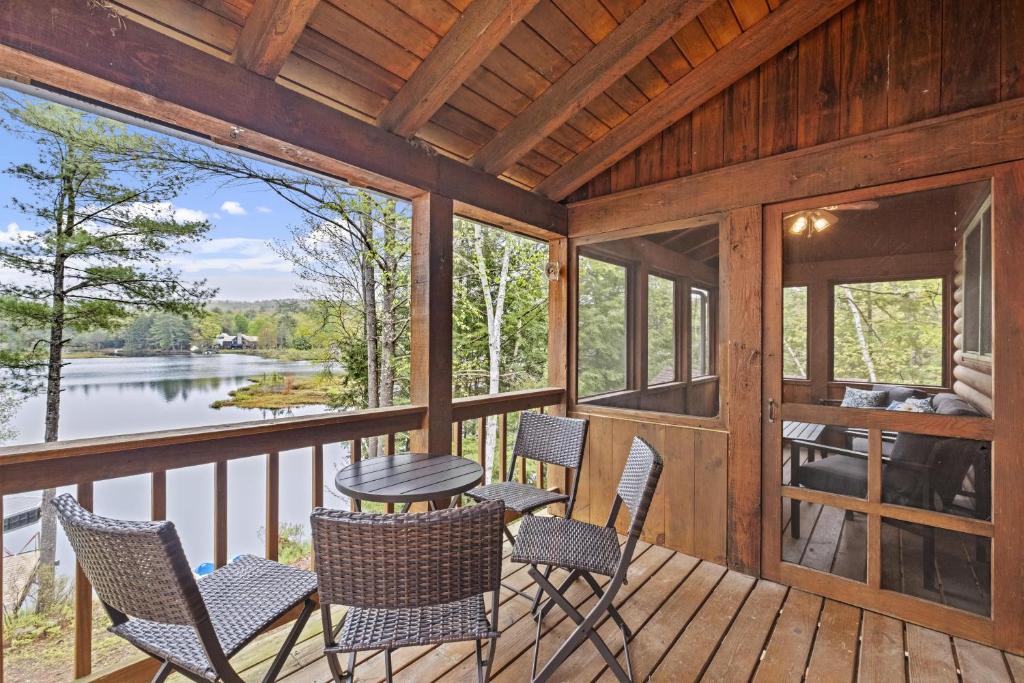 eine abgeschirmte Veranda mit Stühlen und einem Tisch in der Unterkunft Private Lakefront! - Luxury Log House! in Sanbornton