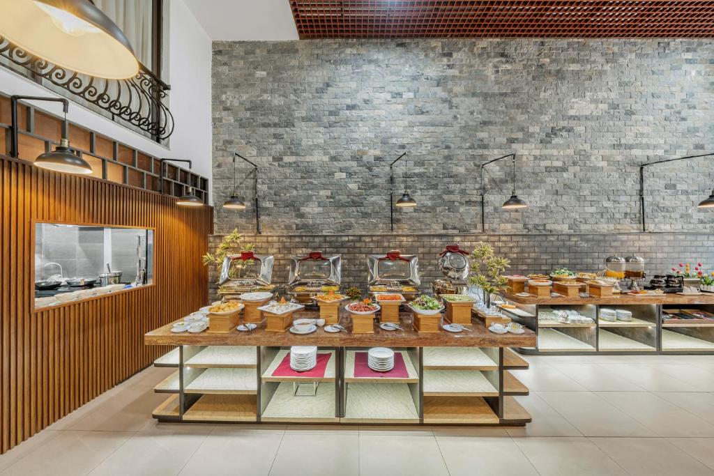 A spacious breakfast buffet room presents multiple serving stations beneath pendant lights.