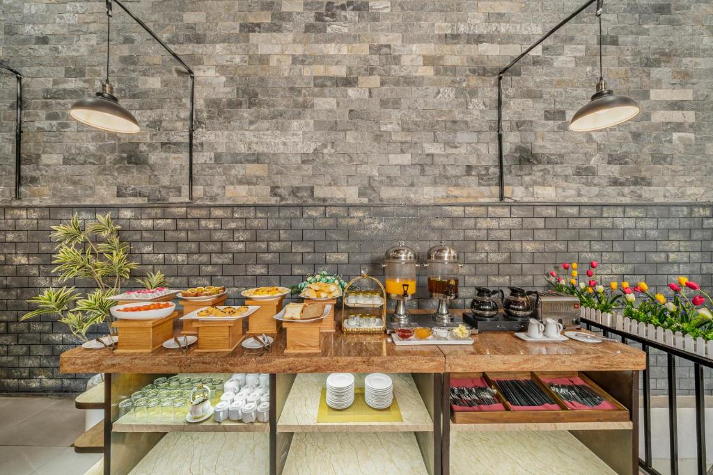 A buffet station offers prepared dishes, drinks, coffee and tableware against a dramatic brick-and-stone wall.