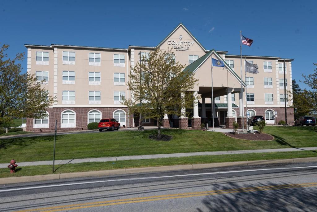 Um edifício com uma bandeira americana à frente. em Country Inn & Suites by Radisson, Harrisburg - Hershey West, PA em Harrisburg