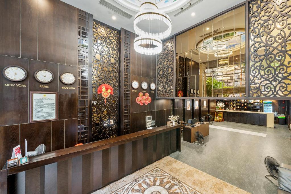 A dark wood reception lobby uses decorative screens, clocks and oversized chandeliers for a theatrical welcome.
