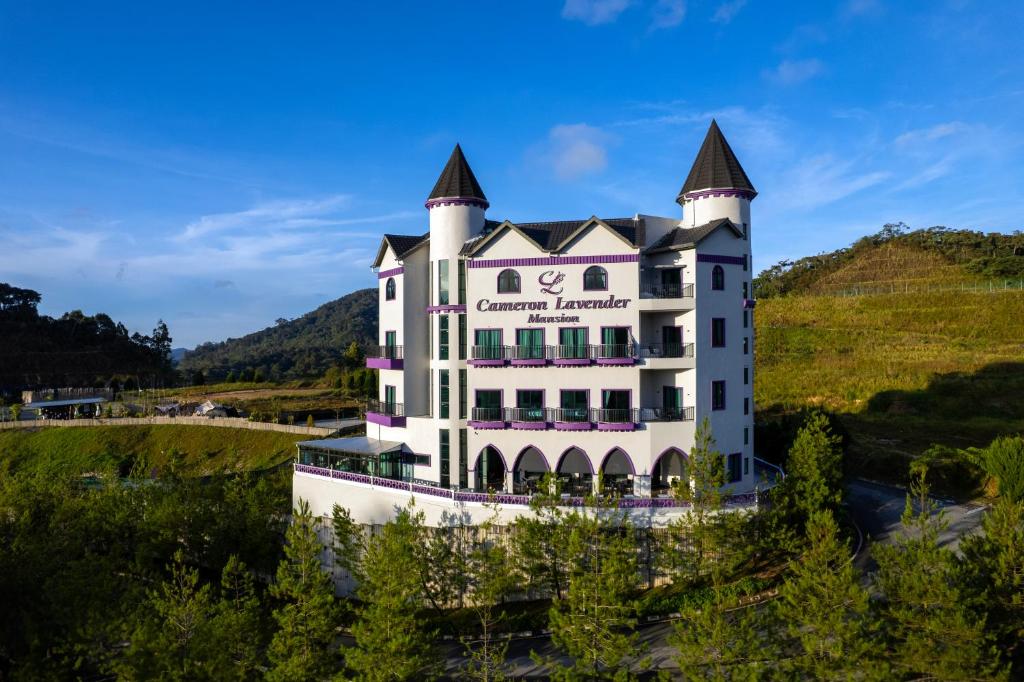 a large white building with a turret on a hill at Cameron Lavender Mansion by PLAY in Brinchang