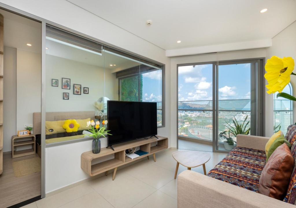 a living room with a flat screen tv and large windows at The Sóng Apartment - Nhà Của Kim in Vung Tau