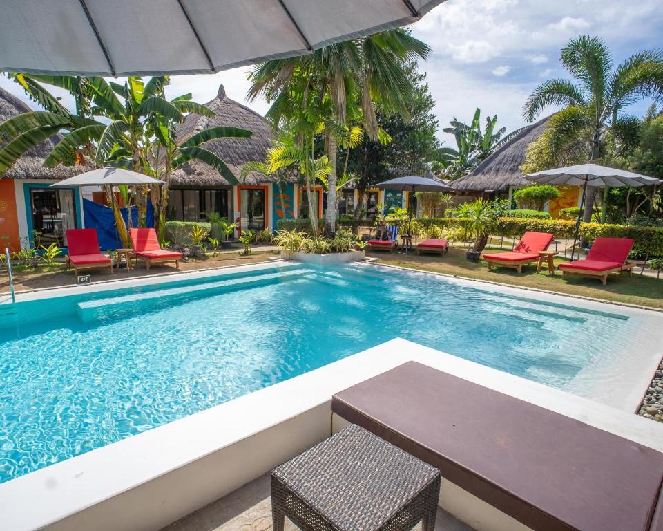 a pool at a resort with chairs and an umbrella at Villa Kasadya in Panglao