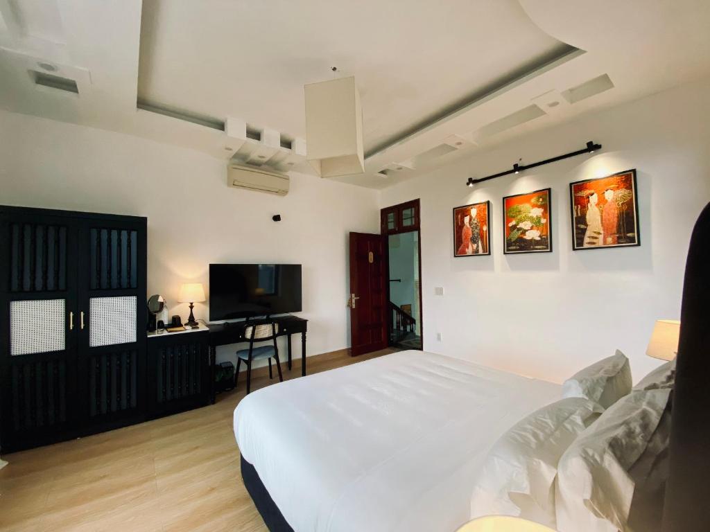 - une chambre avec un lit blanc et une télévision dans l'établissement Viet Hai Lan Homestay, à Cat Ba