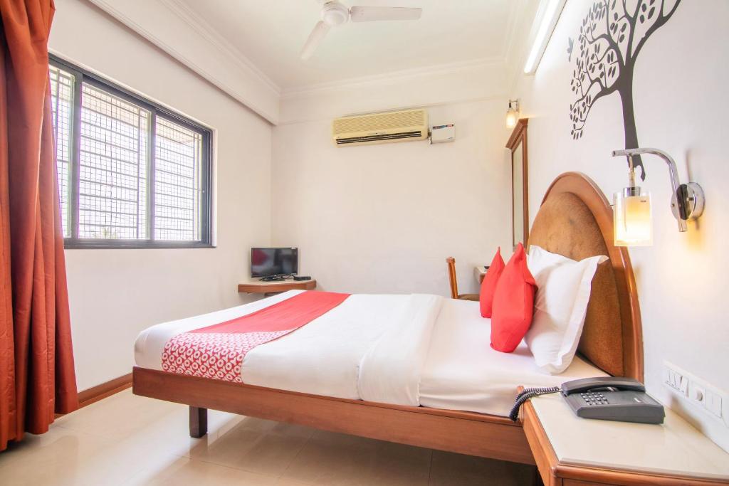 Schlafzimmer mit einem Bett, einem Schreibtisch und einem Fenster in der Unterkunft OYO Hotel Sunil Residency in Bangalore