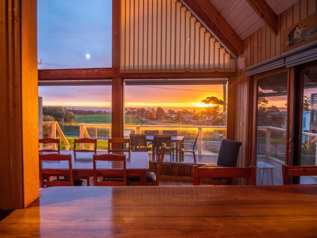 un restaurante con mesa y sillas y vistas a la puesta de sol en Sunset Dreams across the Sea, en Coronet Bay