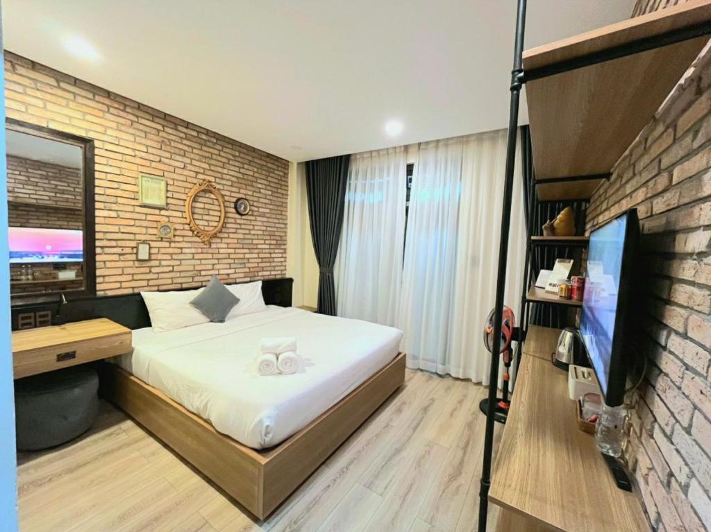 een slaapkamer met een wit bed en een bakstenen muur bij The Brick Home dalat in Da Lat