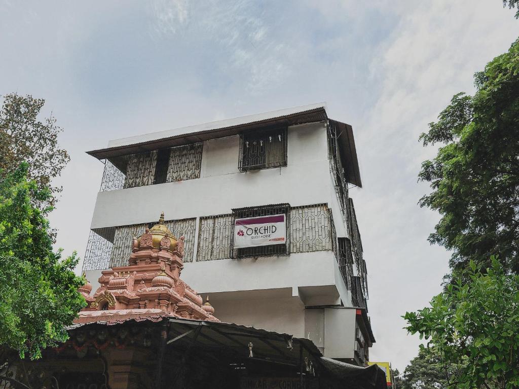 a tall white building with a sign on it at The Orchid Guest House Near Phugewadi Metro Station in Khadki