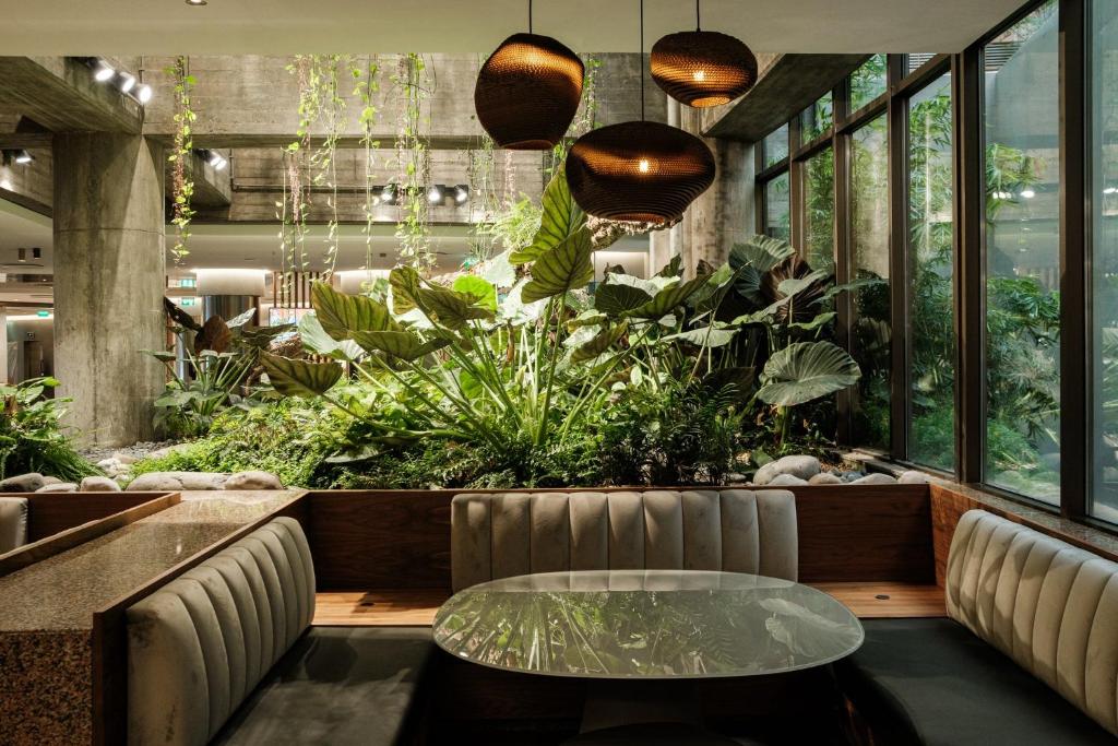 A lounge seating area framed by a dense indoor garden and tall windows.