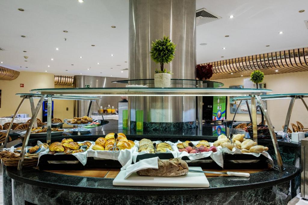 A long breakfast buffet display of breads, pastries and rolls.