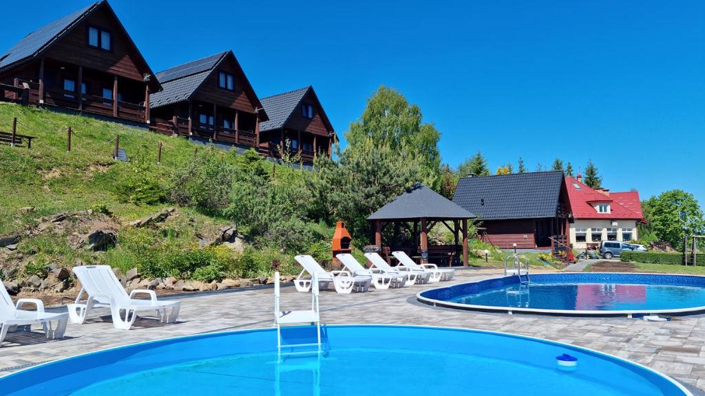 ein Resort mit einem Pool, Stühlen und Häusern in der Unterkunft Na Górce - Domki z Widokiem Na Jezioro i Góry in Polańczyk