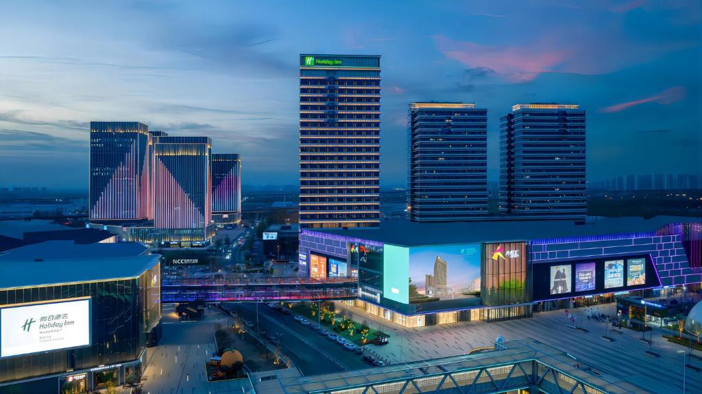 un perfil urbano por la noche con edificios altos en Holiday Inn Tianjin Xiqing, an IHG Hotel, en Tianjin