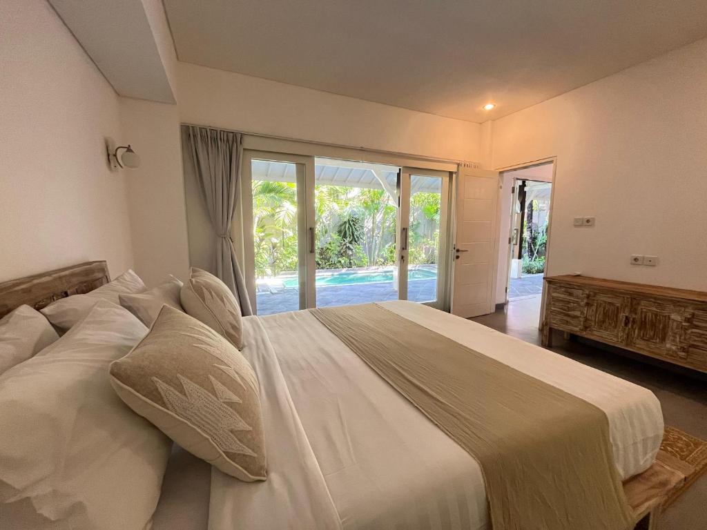 1 dormitorio con 1 cama blanca grande y puerta corredera de cristal en Iris Luxury Private Villa Seminyak 2&3BR en Seminyak