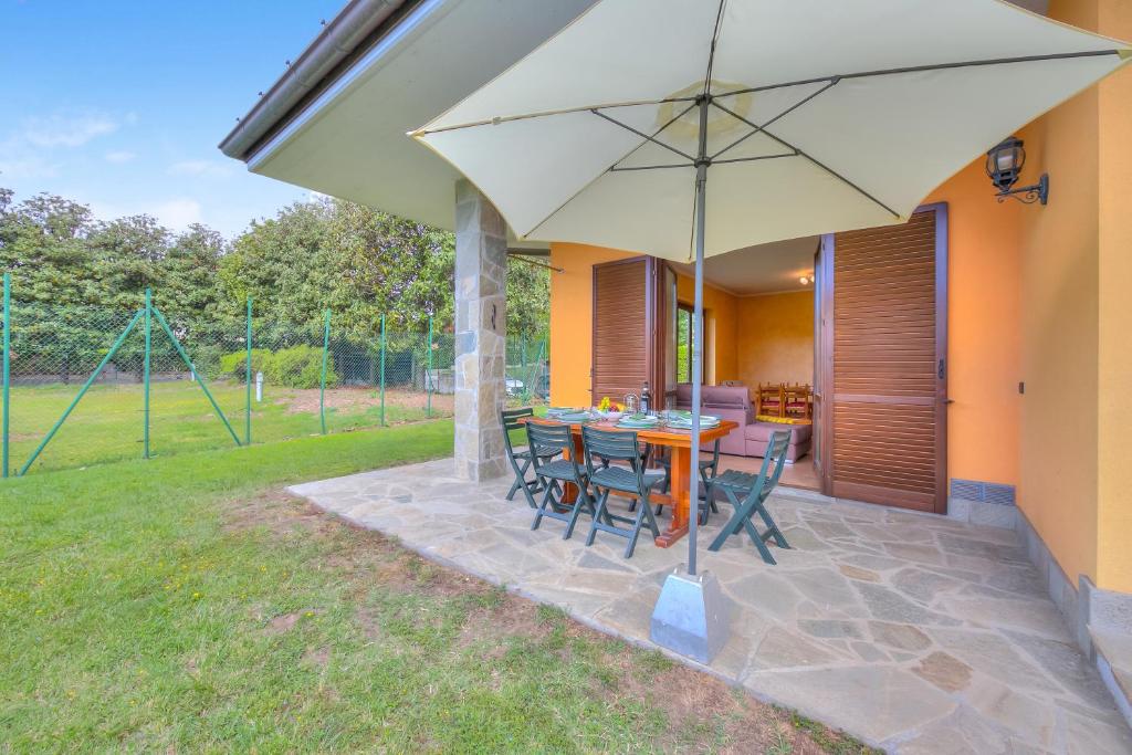 une terrasse avec une table, des chaises et un parasol dans l'établissement Il Sole Di Mirasole - Happy Rentals, à Leggiuno