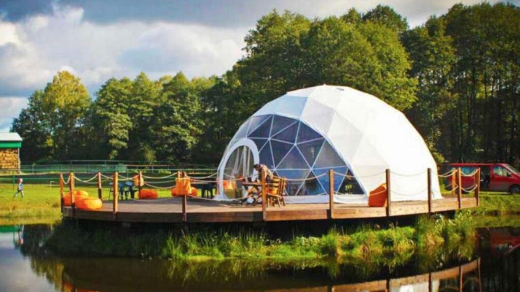 a domed tent on a dock on a body of water at Forest Glamping in Braşov
