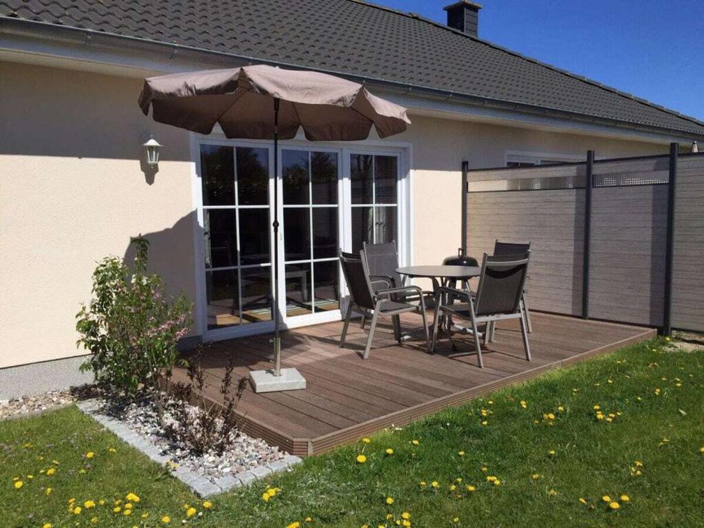un patio con mesa, sillas y sombrilla en Boddensurfer 2b Comfortable holiday residence en Pruchten