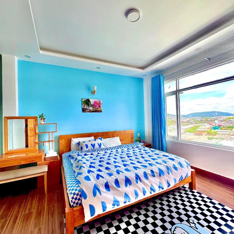 a blue bedroom with a bed and a window at MƠ House in Ấp Kim Thạch