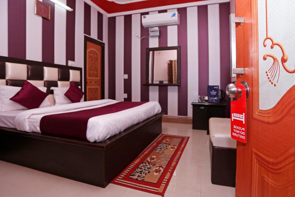 a bedroom with a bed with purple and white stripes at Mehfil Hotel in Jawālāpur