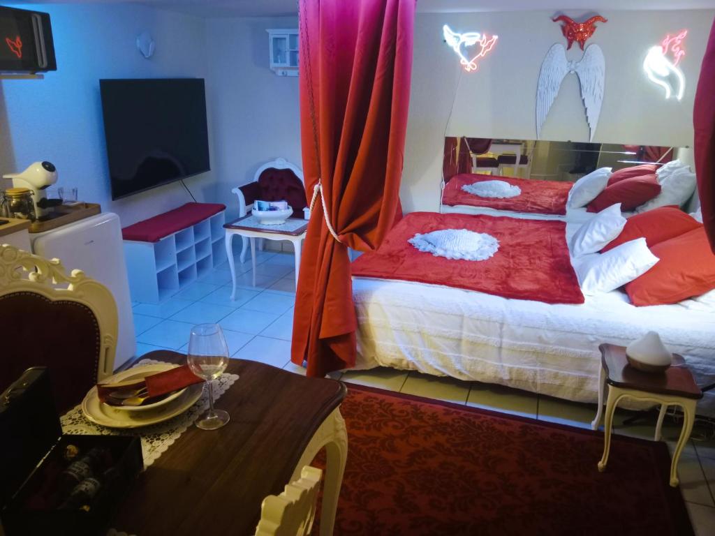 a bedroom with a bed and a tv and a table at Love Room Ange ou Démon à Aulnat in Aulnat