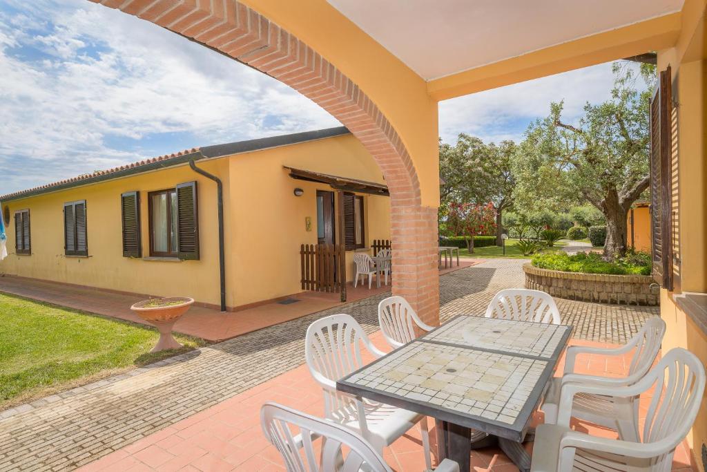 een patio met een tafel en stoelen en een huis bij Il Girasole - Corbezzolo in Venturina Terme