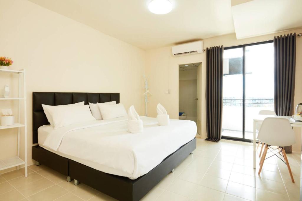 um quarto com uma grande cama branca com almofadas brancas em Bansuay Phranangklao Apartment&Hotel em Ban Sai Ma