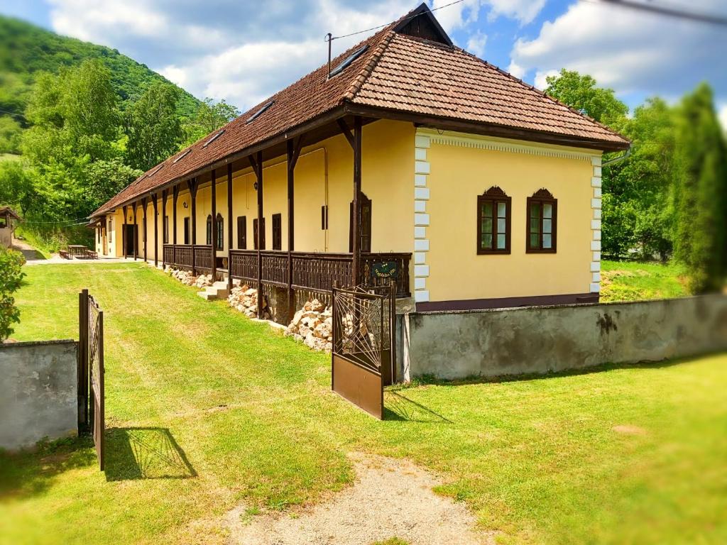 un pequeño edificio amarillo con una valla en el césped en Magdolna Ház, en Szögliget