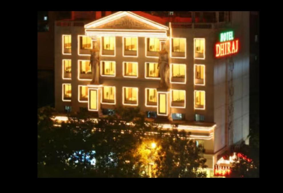 un edificio iluminado con un cartel delante en HOTEL DHIRAJ, en Thane