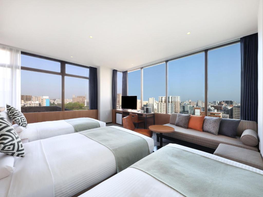 a hotel room with two beds and a couch at HOTEL MYSTAYS Kumamoto Riverside in Kumamoto