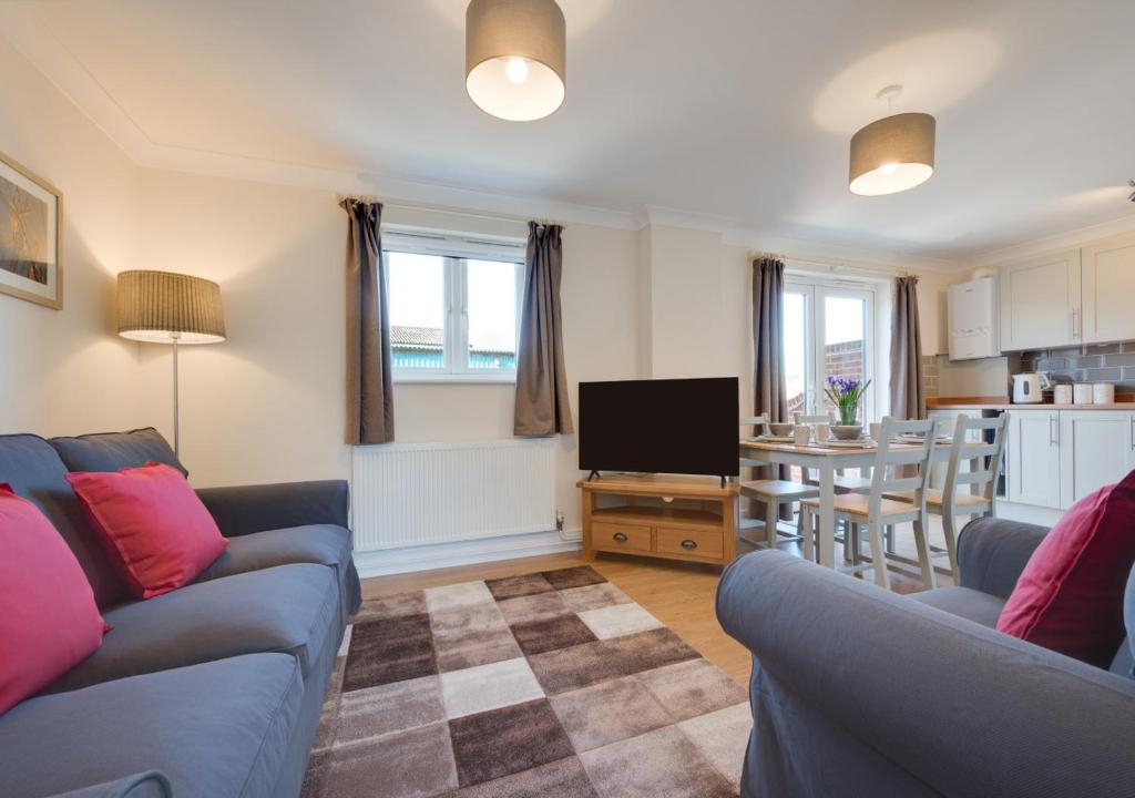 uma sala de estar com dois sofás azuis e uma cozinha em The Cart Lodge em Chedgrave