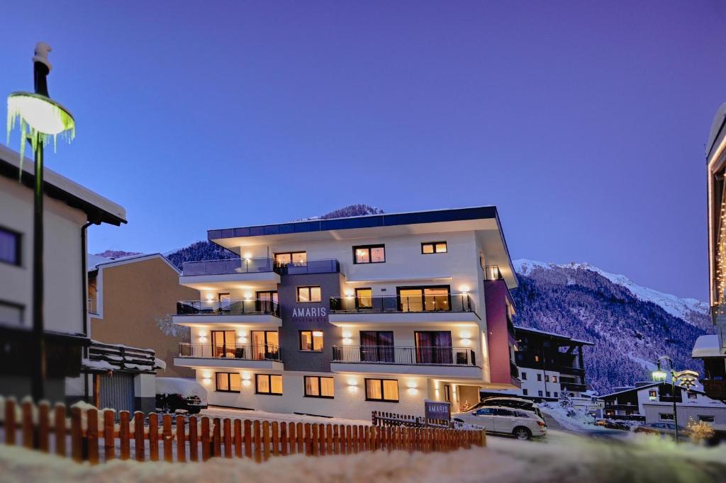 a building with lights on in front of a mountain at Amaris Apartments in Ischgl